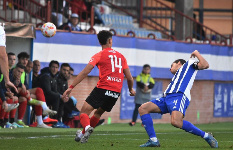 Ilyas Chaira y el central del Talavera Dani Ramos en un lance del partido y con el banquillo del San Fernando CD atento a la jugada. 