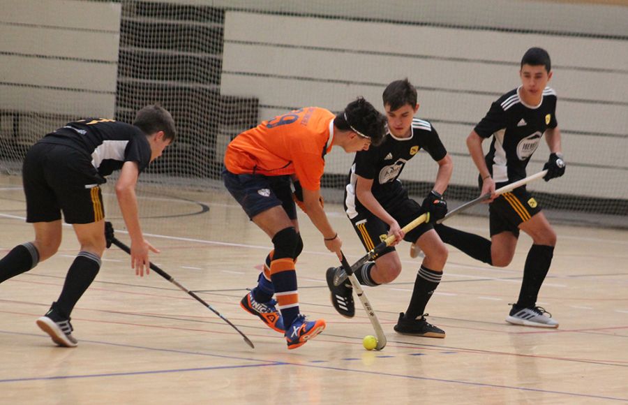 Daniel Sánchez Cabrera, del Club Hockey San Fernando, esconde la bola ante tres jugadores del Atlétic Tarrasa durante el partido matinal. 