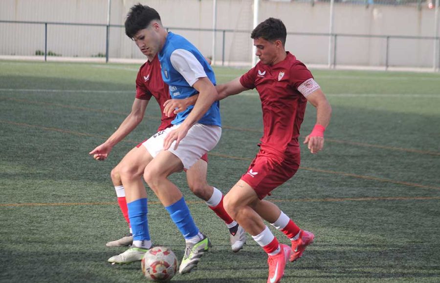 José Pedraza forcejea con dos jugadores del Sevilla FC. 