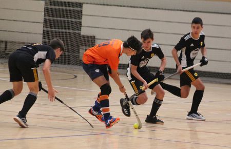 Daniel Sánchez Cabrera, del Club Hockey San Fernando, esconde la bola ante tres jugadores del Atlétic Tarrasa durante el partido matinal. 