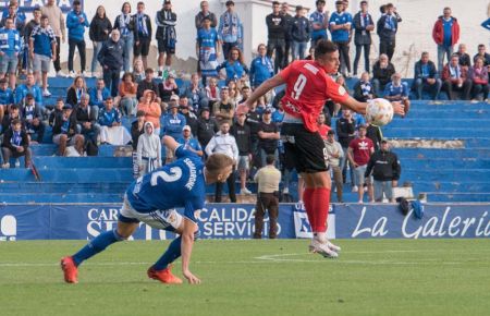 Toni Gabarre se anticipa al argentino Squadrone y con los aficionados del San Fernando CD al fondo.